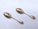 two spoons that are sitting on a white surface