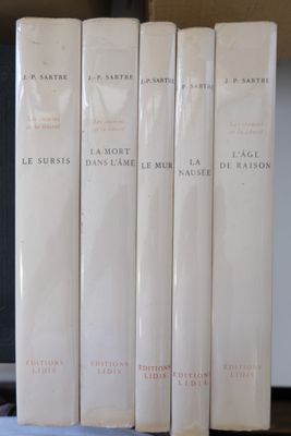 Plusieurs livres sont alignés sur une étagère devant un ordinateur portable