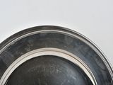 a silver plate with a black rim on a white table