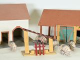 two small toy horses standing in front of a house