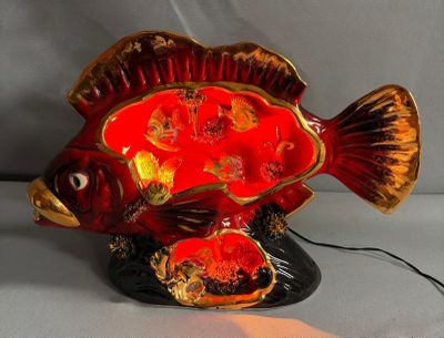 a red fish that is sitting on a black base