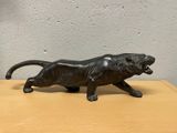 une statue noire représentant un lion posée sur une table en bois