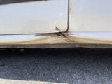 a white car that has some rust on the side of it
