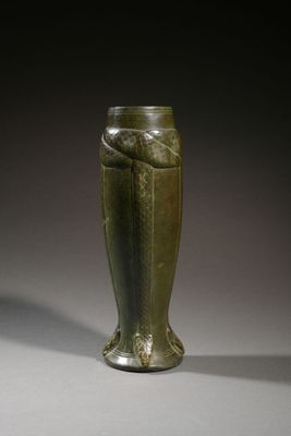 an old green vase sitting on top of a table next to a white wall