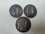 trois pièces d'argent sur lesquelles figurent les portraits d'une femme et d'un homme