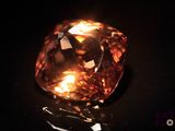 a close up of a fancy orange diamond on a black surface