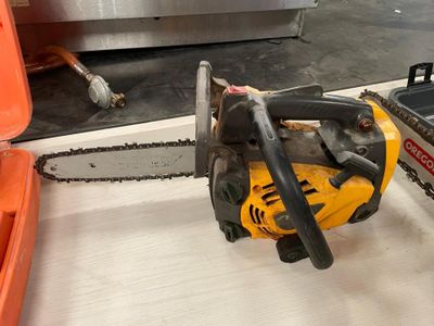 une tronçonneuse posée par terre à côté d'une boîte à outils