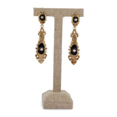 une paire de boucles d'oreilles noires et dorées posée sur un présentoir