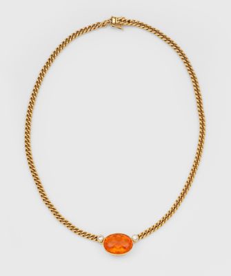 a gold necklace with an orange stone and a pearl bead
