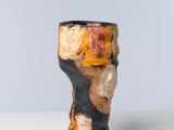 un vase orange et noir posé sur une table blanche