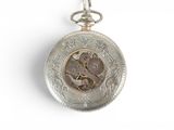 a silver pocket watch on a chain on a white surface