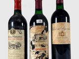 trois bouteilles de vin sont alignées sur une surface blanche