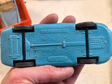 a person holding a blue toy car in their hand