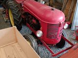 a red tractor parked in a garage next to a crate