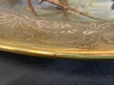 a close up of a gold plate with a bird on it
