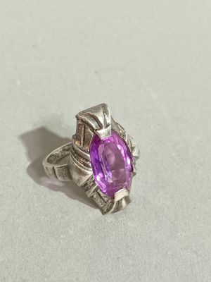a close up of a ring with a purple stone in it