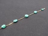 un gros plan d'un bracelet orné de perles de turquoise sur un fond noir