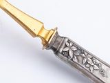 a silver and gold knife with a flower design on the handle