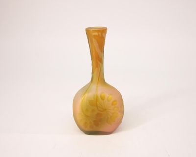 un vase jaune orné d'une fleur, posé sur une surface blanche