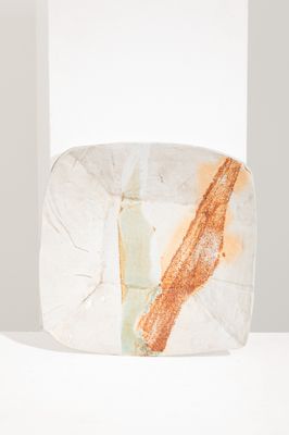 un bloc de marbre orange et blanc posé sur une table blanche