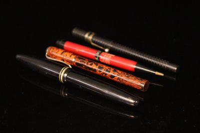 three pens sitting on top of a black surface next to each other