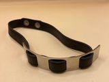 a close up of a black and silver bracelet on a white surface