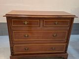 une commode en bois avec des poignées en laiton et des tiroirs