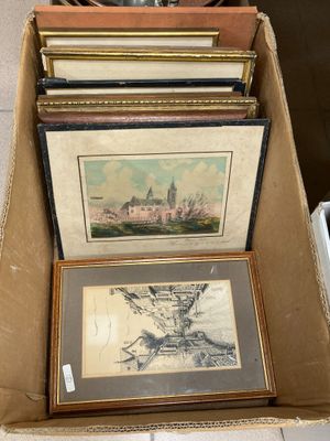 plusieurs tableaux, encadrés ou non, rangés dans une boîte posée sur une table