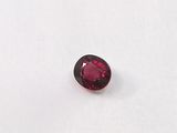 a close up of a red garnet stone on a white surface