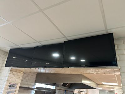 un grand téléviseur à écran plat fixé au plafond au-dessus d'une cuisinière