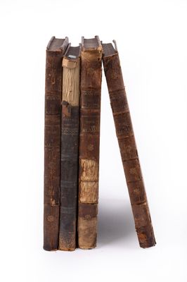 several old books stacked on top of each other on a white surface