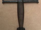 a close up of a knife on a wall with a cross on it