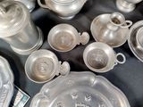 a lot of silver dishes and cups on a table