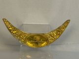 a gold plate on a clear stand on a white surface
