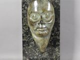 a close up of a sculpture of a face on a marble block