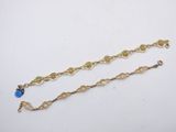 a close up of a gold chain with a blue stone on it