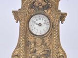 a gold clock that is sitting on a white surface