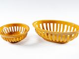 une paire de paniers à fruits en plastique jaune sur fond blanc