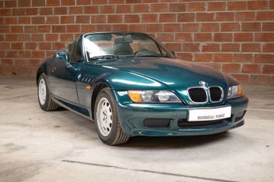 a blue bmw sports car parked in front of a brick wall