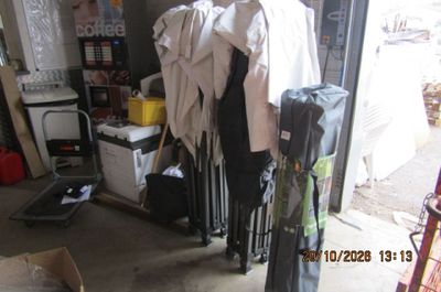 une photo d'un garage en désordre avec des vêtements suspendus à un portant