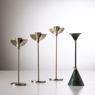 un ensemble de quatre bougeoirs en laiton posés sur une table blanche