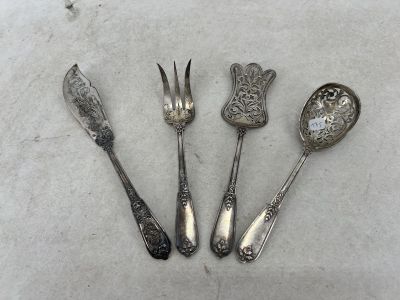 quatre cuillères et une fourchette en argent sur une surface blanche
