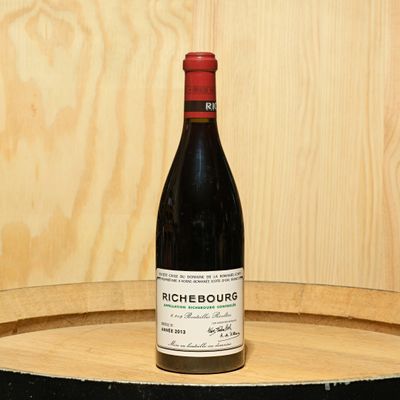 a bottle of wine sitting on top of a barrel