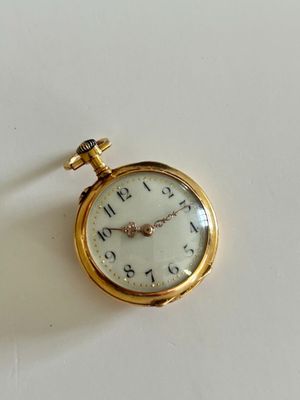 a gold pocket watch sitting on a white surface