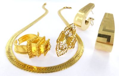 a gold necklace, bracelet, and ring on a white surface