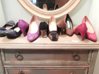 several pairs of shoes are lined up on a dresser in front of a mirror