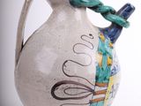 a white vase with a blue handle on a white background