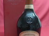 an image of a bottle of champagne next to a box on a pink background