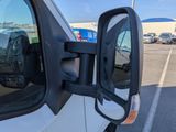 a side view mirror of a white van in a parking lot