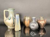 cinq vases différents posés sur une table, sur fond gris